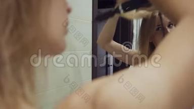 漂亮的女人在浴室洗澡后用刷子烘干机烘干头发。